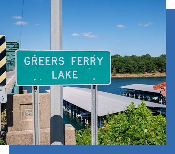 A green sign that says greeers ferry lake.